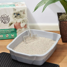 Cat litter tray filled with pale beige granules and metal litter scoop