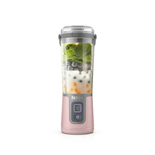 Dusty pink portable personal blender with clear cup and gray lid, filled with greens