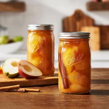 Wide-mouth glass mason jar with metal lid and band, filled with amber fruit preserves