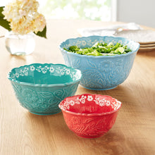 Three embossed stoneware serving bowls in light blue, teal green, and red.