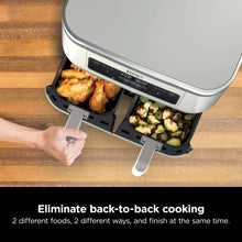 Dual-basket air fryer with baskets open, chicken and roasted vegetables inside