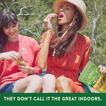 Nature Valley protein granola pouch in a yellow packet, outdoors beside seated people.