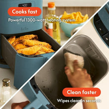 Surf blue air fryer with open basket of cooked food and hand wiping interior