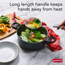 Spider wok strainer scooping vegetables from a pot; long handle with round mesh basket