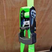 Ratchet tie-down attachment with green webbing, black ratchet handle, and mounting loop