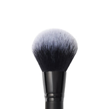 Face brush with dense gray bristles and black handle, centered close-up