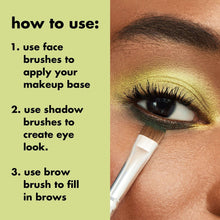 Makeup brush applying product to an eyelid with dense bristles on a white handle
