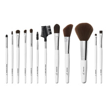 Complete set of makeup brushes with brown bristles and white handles arranged in a row
