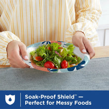 Disposable paper plate with leaf pattern holding salad greens and tomatoes
