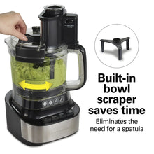 Food processor with built-in bowl scraper, black blender top, and clear bowl with chopped greens