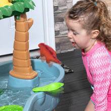Child splashing at the blue dino water table with orange dinosaur figure
