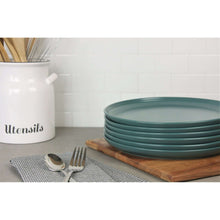 Emerald green round stoneware dinner plates stacked on wooden board