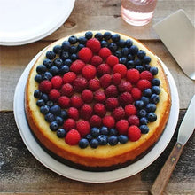 White paper dinner plate with a berry tart topped with blueberries and raspberries