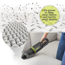 Green cordless handheld vacuum cleaning upholstery with crevice-style nozzle
