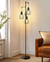 Black industrial standing floor lamp with four wire cage shades in a living room