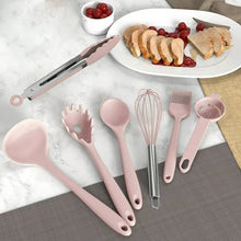 Pink silicone cooking utensil set laid out, including spatula, whisk, and spoon