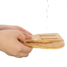 Hand using wooden spatula to spread dough on a baking surface