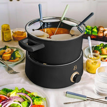 Black electric fondue pot with stainless lid and six forks on heating base
