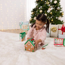 Child attaching the green-iced roof to the wooden gingerbread house