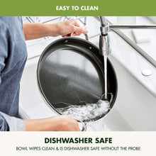 Electric skillet being rinsed in a sink with water flowing over the pan