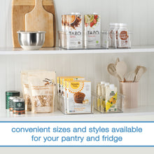 Clear plastic organizer bin on a shelf with kitchen pantry and countertop items inside.