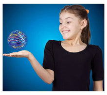 Child reaching toward a small floating ball toy while holding one arm out