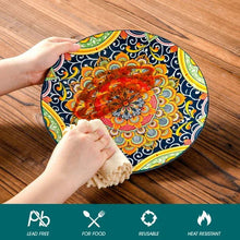 Boho patterned ceramic plate held by hands on a table, blue orange mandala