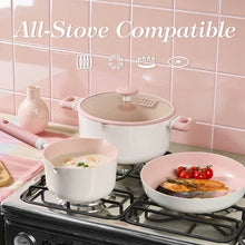 Pink ceramic nonstick pots and pans on a gas stove with matching lids