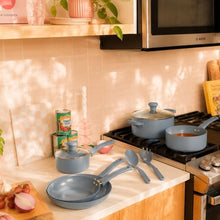 Blue ceramic non-stick pots and pans on stove with utensils nearby