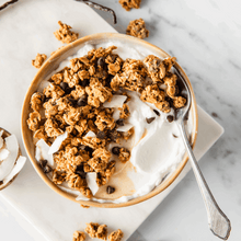 Bowl of granola with chocolate chips over yogurt, with spoon beside it