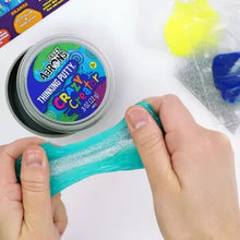 Teal thinking putty being shaped by hands next to a round thinking putty tin