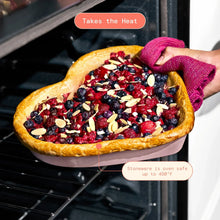 Heart-shaped stoneware baking dish on an oven rack with berry pastry inside