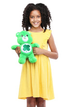 Green plush teddy bear held in front of a child’s chest