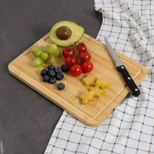 Bamboo cutting board with fruit and knife; juice groove section on right