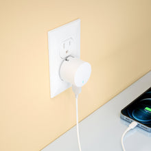 White USB-A wall charger plugged into outlet with Lightning cable connected.