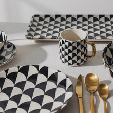 Black and white geometric stoneware mug with gold-tone handle, close-up