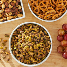 Bowl of lightly salted shelled pistachios, with two other bowls and scattered nuts
