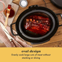 Black slow cooker with lid open, showing cooked red meat inside the oval insert