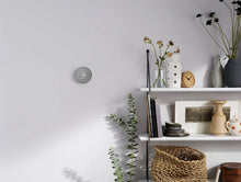 Wall-mounted smart thermostat with 75 display on an interior wall