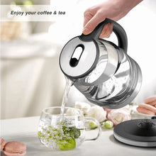Electric glass kettle pouring water from black-handled spout into glass cup