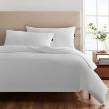 White bed pillows with blue corner tags on a bed, king size
