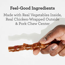 Hand holding stuffed twist dog chew, chicken-wrapped with pork center