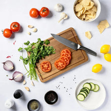 Acacia wood cutting board with diced tomatoes, herbs, and two triangle anti-slip grips