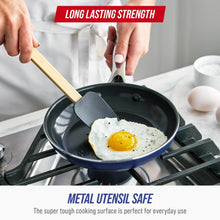 Ceramic nonstick frying pan with silicone-tipped wooden spatula on a stovetop burner