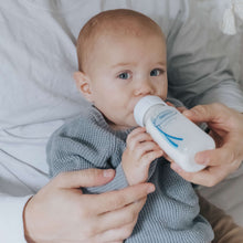 Narrow anti-colic baby bottle with white nipple while baby drinks