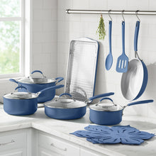 Blue ceramic cookware set on countertop with hanging utensils and drying rack
