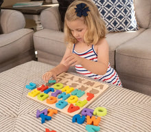 Wooden alphabet puzzle on a couch blanket with colorful letter blocks and a child