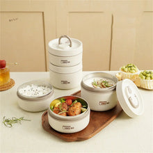 Stacked white insulated lunch food containers with open lids on a serving surface