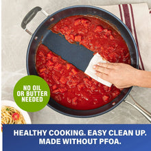 Blue nonstick skillet with red sauce and hand holding a cloth