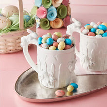 White bunny-themed mugs filled with colorful speckled egg candies